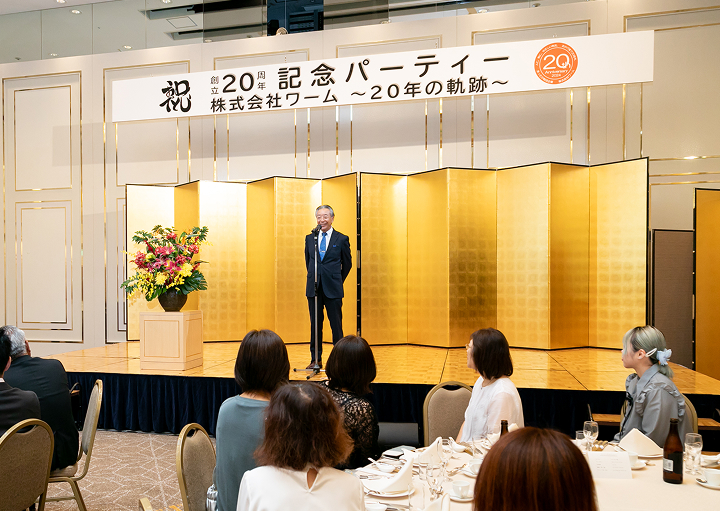 株式会社ワーム創立20周年記念パーティーで屏風の前で挨拶している様子