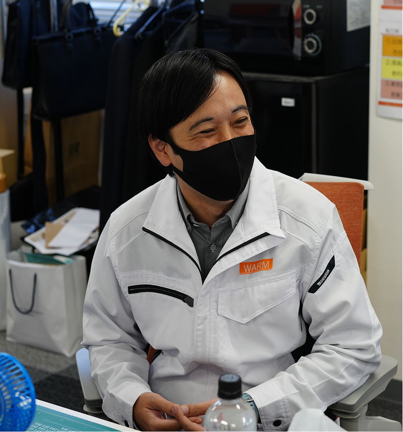 黒いマスクを着用した男性が、事務所内で談笑している様子